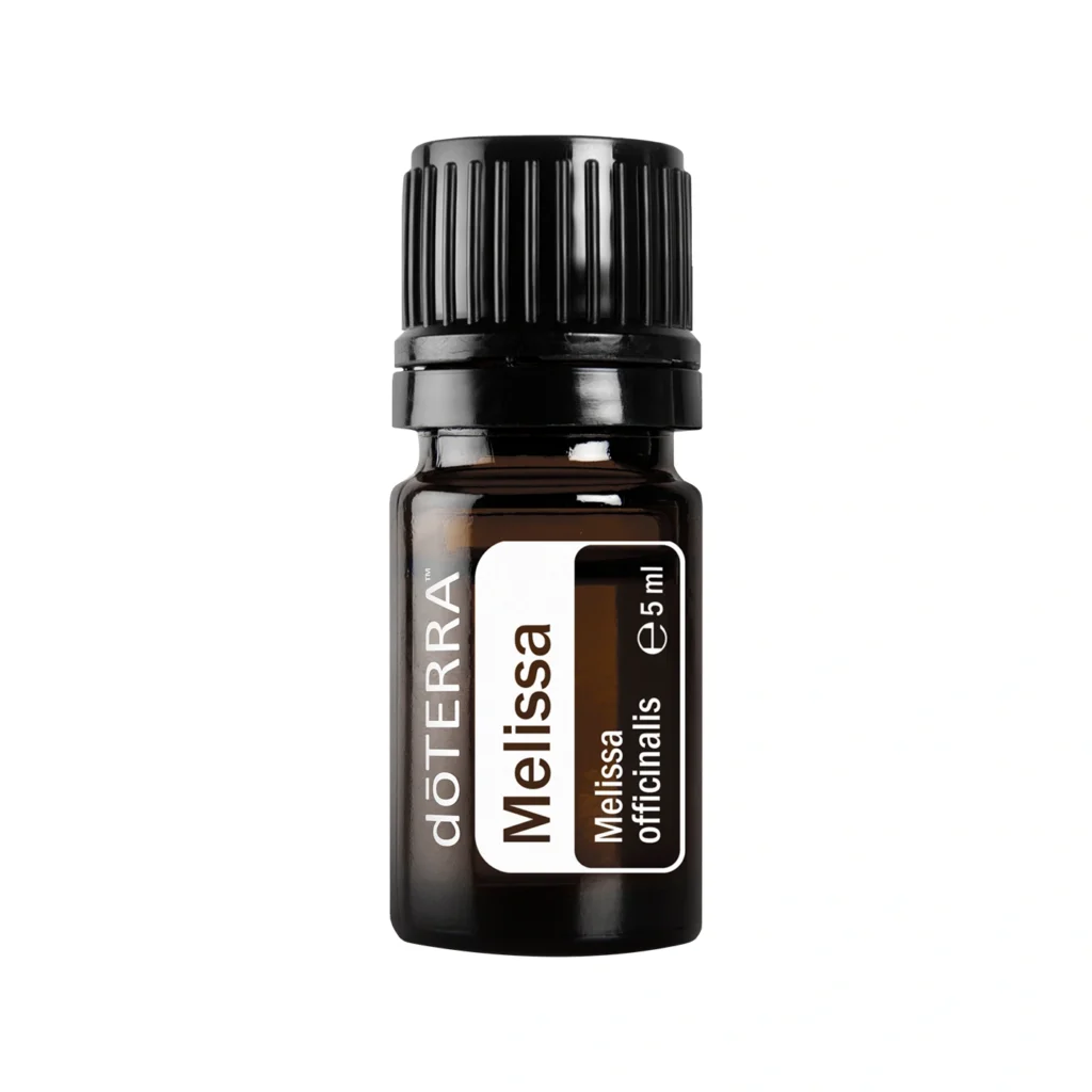 Frasco de Aceite Melissa doTERRA junto a hojas frescas de melisa.